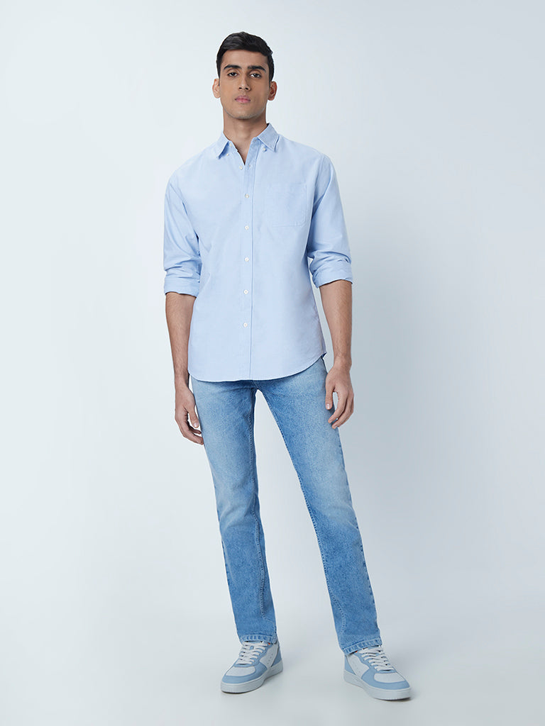 A calm relaxed man wearing a light blue shirt with beige pants, standing  against a white background. Carefree and relaxed looking at camera. Stock  Photo | Adobe Stock